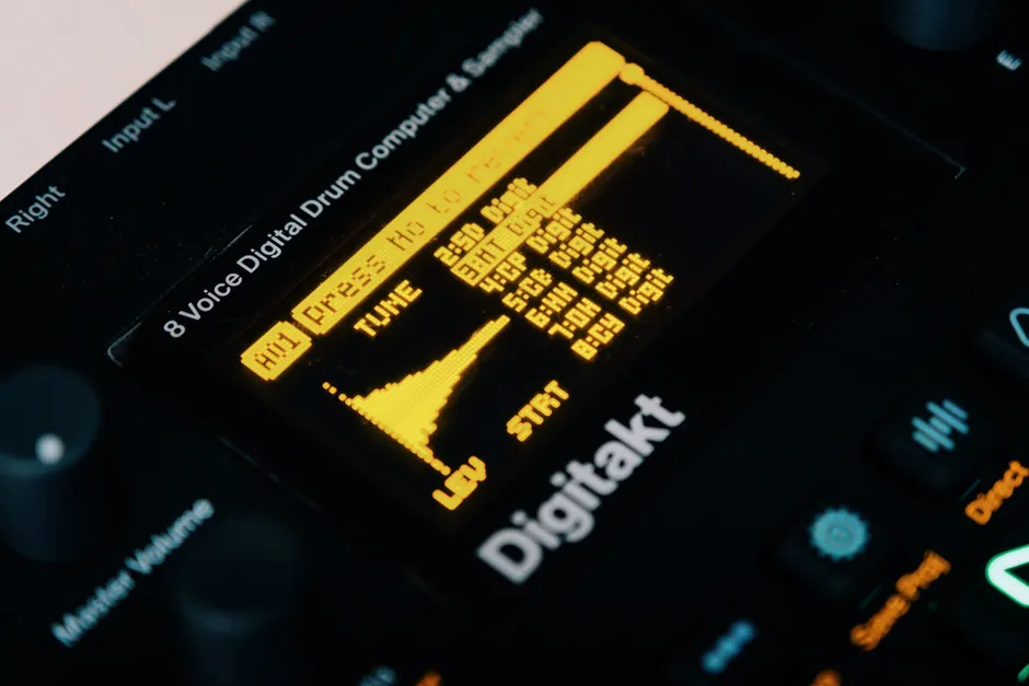 Close-up view of an Elektron Digitakt drum machine with visible OLED display and controls.
