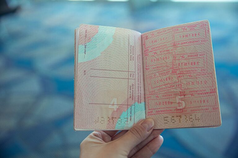 Apple conseille à certains salariés H-1B de rester aux États-Unis : jusqu’à 12 mois de délai Close-up view of an open passport displaying various travel stamps in an airport setting.