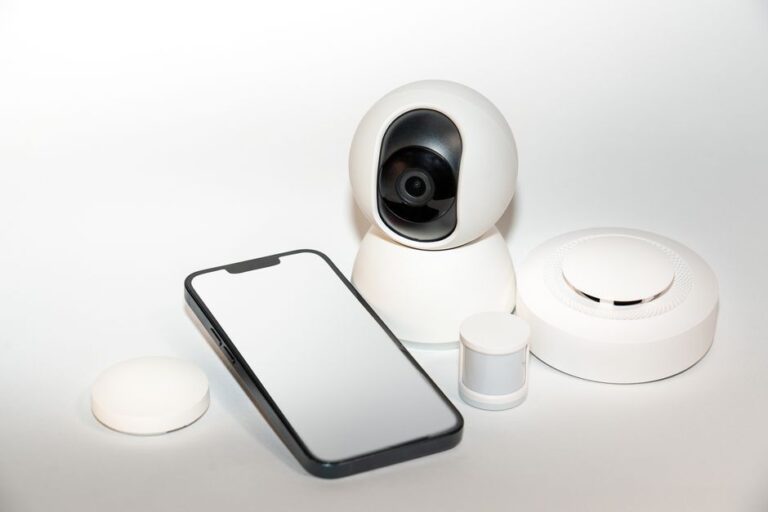 Home Hub Apple 2026 : écran, caméra et Siri, le jardin clos change de pièce Collection of smart home security gadgets with a smartphone display.