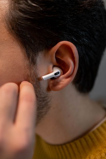 Detailed close-up of a person wearing wireless earbuds, showcasing modern tech use.