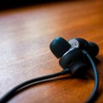 AirPods Pro et audition : 35 adultes, des gains mesurés, sans miracle Detailed close-up of black earbuds resting on a polished wooden table, showcasing modern technology.