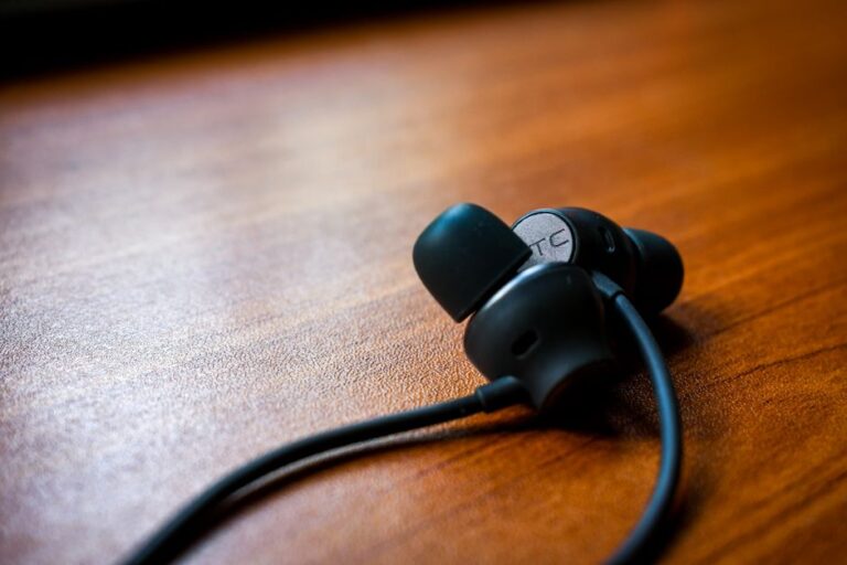 AirPods Pro et audition : 35 adultes, des gains mesurés, sans miracle Detailed close-up of black earbuds resting on a polished wooden table, showcasing modern technology.