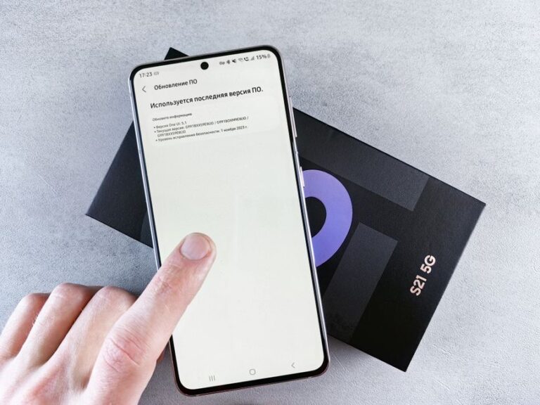 iOS 26.2 corrige 25 failles: WebKit n’a plus carte blanche Finger interacting with smartphone on software update screen above phone box, isolated on light background.