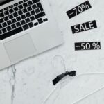 Cyber Monday 2025 : Disney+ à 4,99 $, Apple TV+ à 5,99 $, le piège du renouvellement Flat lay of a laptop, hanger, and sale stickers on a marble desk, ideal for Black Friday themes.