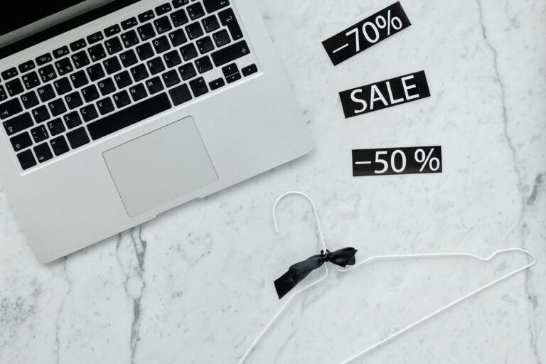 Cyber Monday 2025 : Disney+ à 4,99 $, Apple TV+ à 5,99 $, le piège du renouvellement Flat lay of a laptop, hanger, and sale stickers on a marble desk, ideal for Black Friday themes.