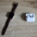 AirPods Pro 3 à 199 $ le 3 septembre 2026 : la promo qui pique Flat lay of a smartwatch and wireless earbuds on a wooden surface, emphasizing modern EDC essentials.