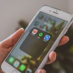 Apple Music Replay 2025 : retrouver ses tops sans jouer à cache-cache Hand holding a smartphone displaying popular music apps like Spotify and Shazam in a close-up shot.