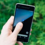 Apple revoit App Tracking Transparency en 2026, Berlin serre la vis Hand holding smartphone with app icon on screen, showcasing modern technology outdoors.
