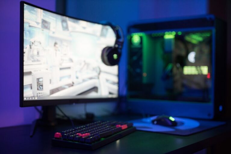 LG UltraGear GM9 : 5K à 165 Hz, le blooming sous surveillance High-tech gaming setup featuring a curved monitor, RGB keyboard, and vibrant lighting.