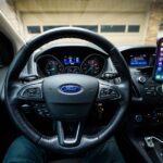 Ford garde Apple CarPlay en 2025, mais freine sur Ultra Interior view of a Ford car featuring a steering wheel, dashboard, and mobile device mount.