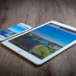 iPad 11 à 274 dollars au Black Friday 2025 : le prix tombe, Apple Intelligence reste dehors iPad and iPhone showing a scenic landscape on a wooden table, highlighting portability and technology.