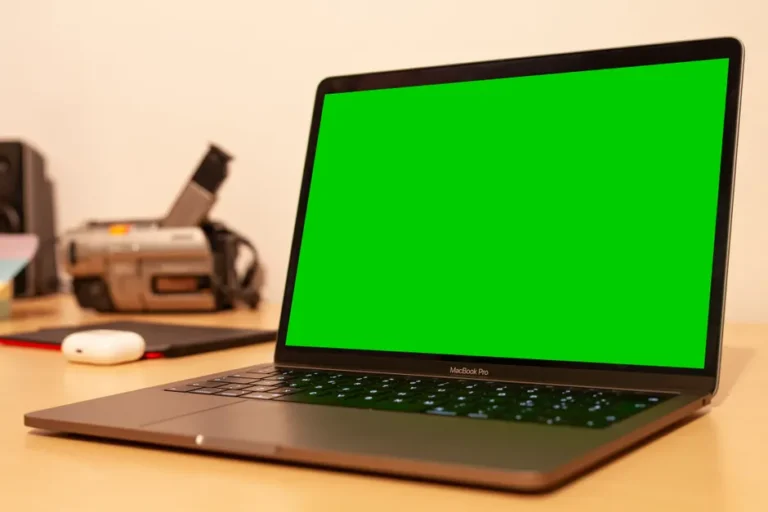 Studio 2025 d’Andrew O’Hara : 32 To, un Nikon Z8 et des câbles partout MacBook Pro with green screen on desk, ideal for video editing setups or tech presentations.