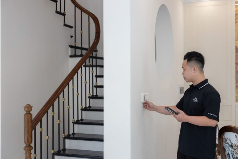Honeywell Home X8S : Matter chauffe le thermostat premium Man adjusting thermostat in stylish home with elegant staircase.