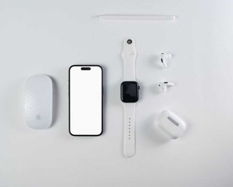 Promotions Apple du 16 décembre 2025 : iPad à 279 $, Mac à 479 $, le Père Noël fait les comptes Minimalist flat lay of smartphone, smartwatch, wireless earbuds, and mouse on a white background.