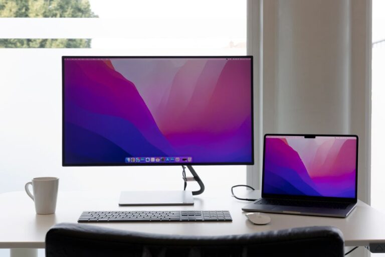 Minimalist workspace featuring dual monitors, keyboard, and a laptop on a clean desk.
