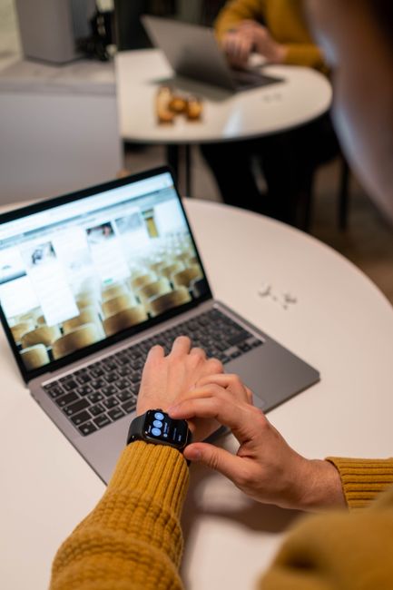 Modern office scene with adult using laptop and smartwatch, emphasizing tech integration.