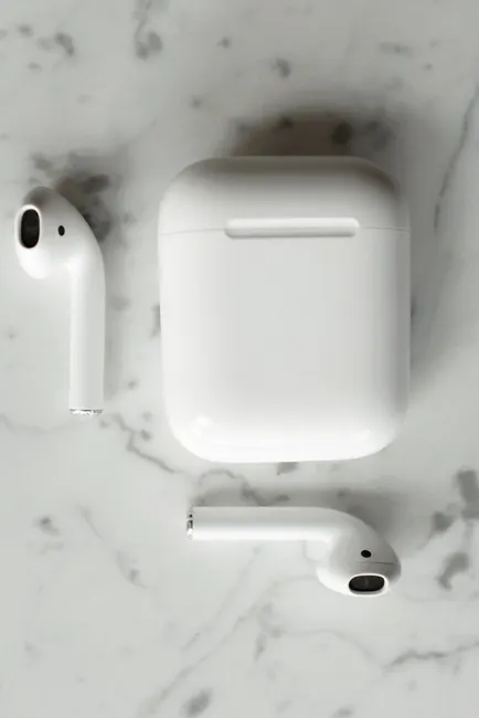 Modern wireless earbuds and charging case on a sleek marble background.