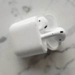 AirPods 4 à 69 dollars au Black Friday 2025 : l'ANC reste au vestiaire Modern wireless earphones in a sleek charging case on a marble surface.