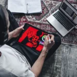 Person using a digital tablet for drawing and design work at home with a laptop.