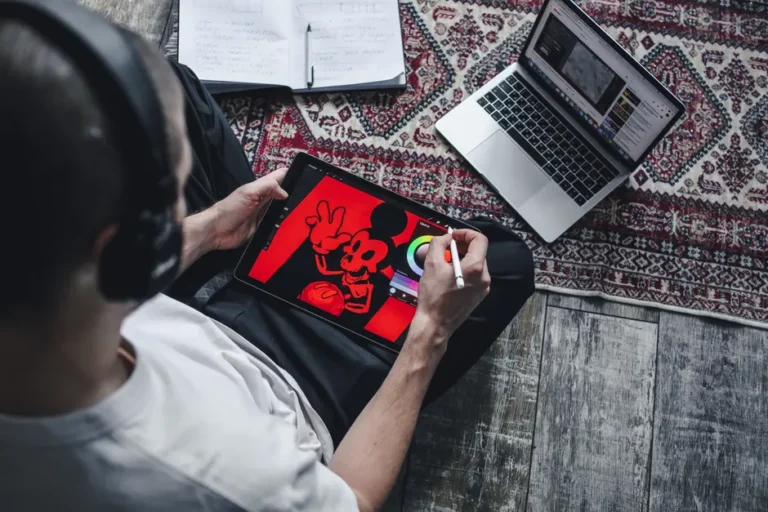 FileMaker Pro : la base Apple qui fabrique des applis métier Person using a digital tablet for drawing and design work at home with a laptop.