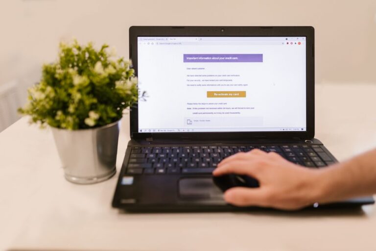 Faux e-mails Prime Video : le PDF qui vous piège Person using a laptop to read an email indoors beside a potted plant.