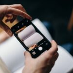 Apple Books 2025 : le bilan de lecture sort du bois Person using smartphone to photograph blank open book. Concept of mobile photography and creativity.