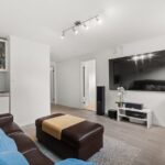Black Friday 2025 : 2 100 $ de remise sur le Samsung S90F 83 pouces Spacious living room featuring a leather sofa, large TV screen, and contemporary decor.