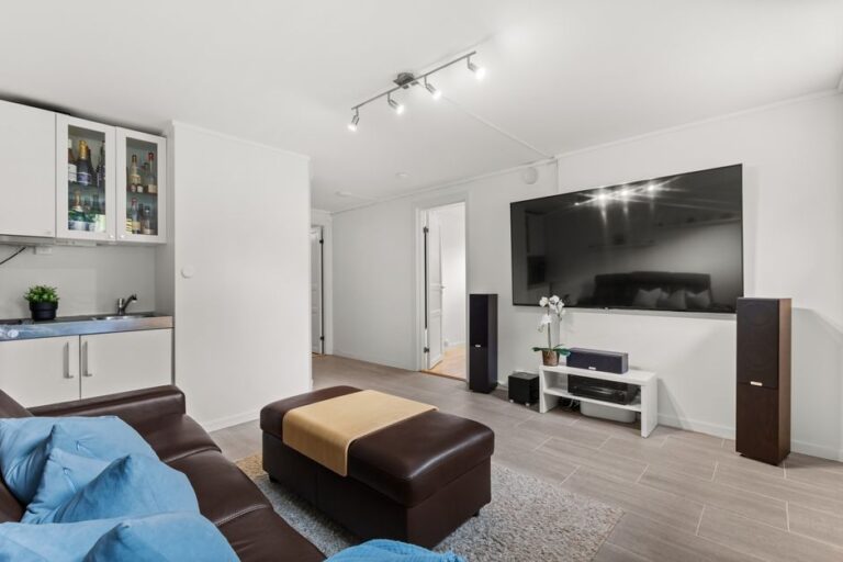 Black Friday 2025 : 2 100 $ de remise sur le Samsung S90F 83 pouces Spacious living room featuring a leather sofa, large TV screen, and contemporary decor.