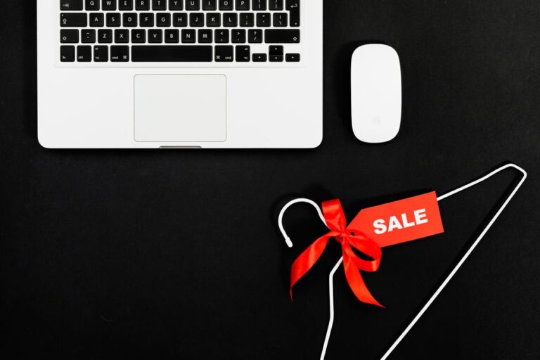 MacBook Air en promo fin 2025 : M4 à 749,99 $, M1 à 499 $ Stylish flat lay of a laptop, mouse, and sale tag on a hanger for online shopping concept.