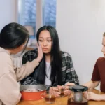 Imperfect Women arrive le 18 mars 2026 sur Apple TV, Weisman rempile Three women at a table offering emotional support and comfort to a friend, fostering compassion and empathy.