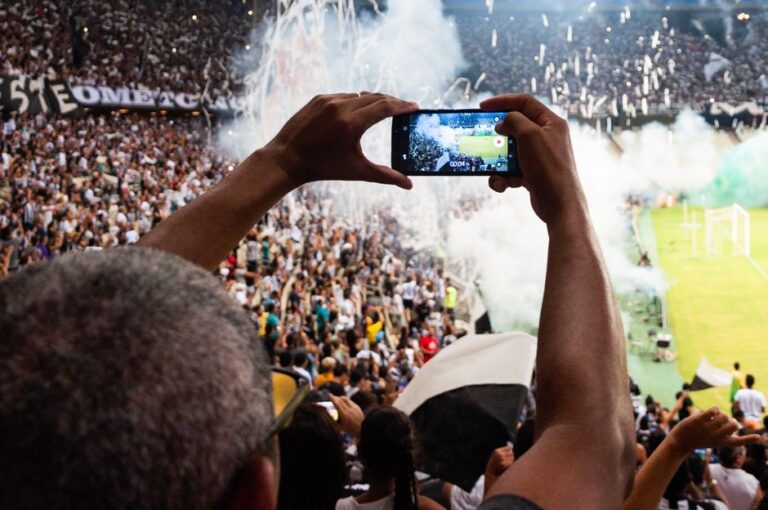 L’iPhone 17 Pro filme un match de MLS en direct, mais le gazon riposte Thrilling football match scene with fans capturing the moment on a smartphone from the stadium stands.