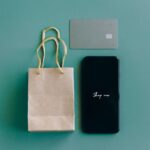 Apple en Inde : 38 milliards en jeu autour de l'App Store Top view of smartphone with 'Shop now' text, credit card, and paper bag on green background.