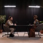 Two hosts recording a podcast in a well-lit studio setup with microphones and studio lights.