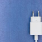 White electric charger plug on a blue textured surface, ideal for tech visuals.