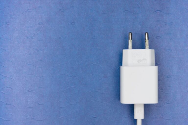 PlugBug Find My : 120 W pour ne plus perdre son chargeur White electric charger plug on a blue textured surface, ideal for tech visuals.