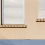 GE Smart Shades à 299,99 dollars : Apple Home baisse les stores au CES 2026 A beige building facade with closed white roller blinds and minimal architectural design.