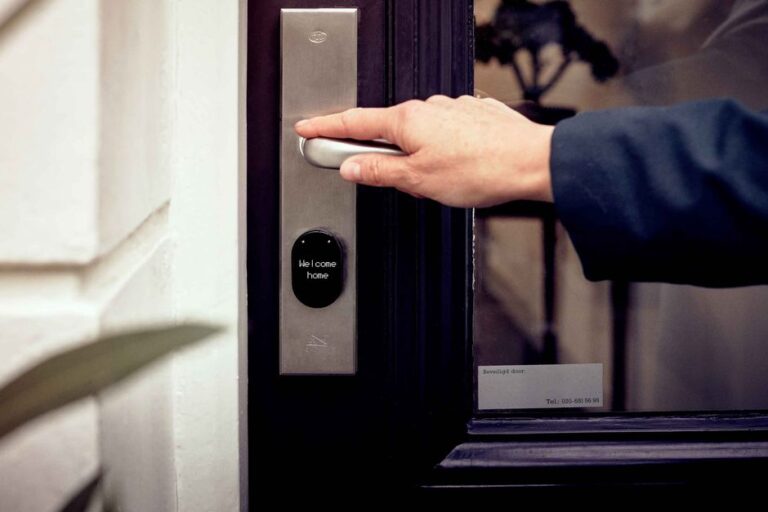 SwitchBot au CES 2026 : serrures 3D, robot et lampe A hand opening a smart home door with digital access panel, conveying security and technology.
