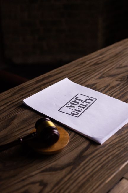A legal gavel next to a 'Not Guilty' document on a wooden table, symbolizing justice.