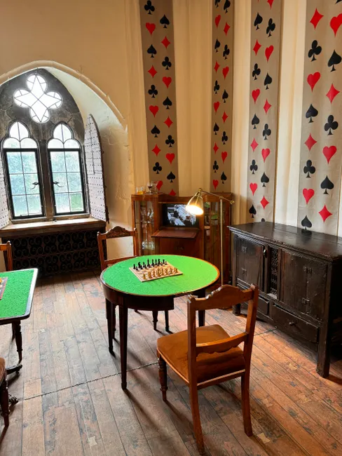 A luxurious game room at Leeds Castle featuring chessboard, classic furniture, and card-themed decor.