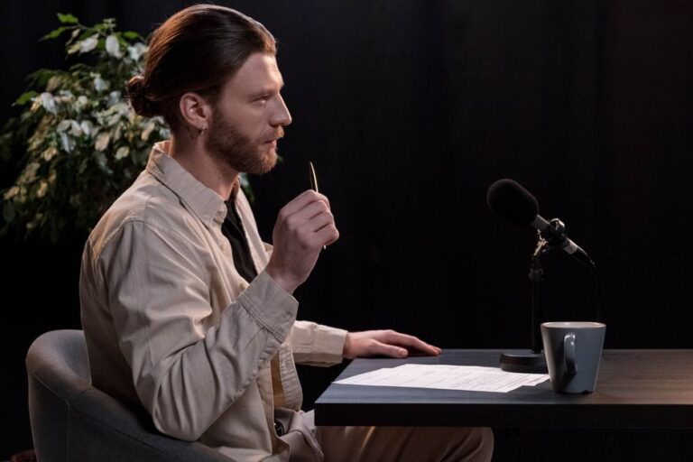 Apple Intelligence en 2026 : Tony Fadell tacle l’IA et le projet automobile A man recording a podcast in a professional studio environment, engaging with a microphone.