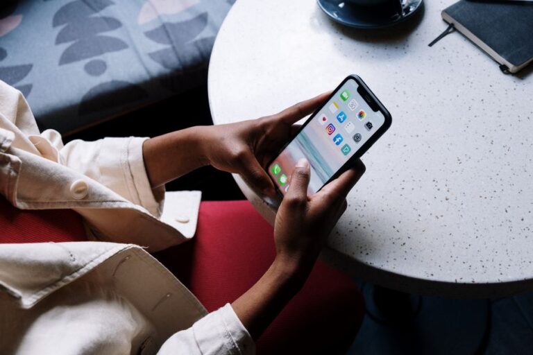 Setapp Mobile ferme le 16 février 2026 : le DMA ouvre, Apple garde le péage A person checks social media apps on a smartphone while sitting at a café table.