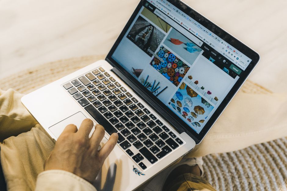 A person using a laptop to browse stock photo websites. Freelancing work in a cozy setting.