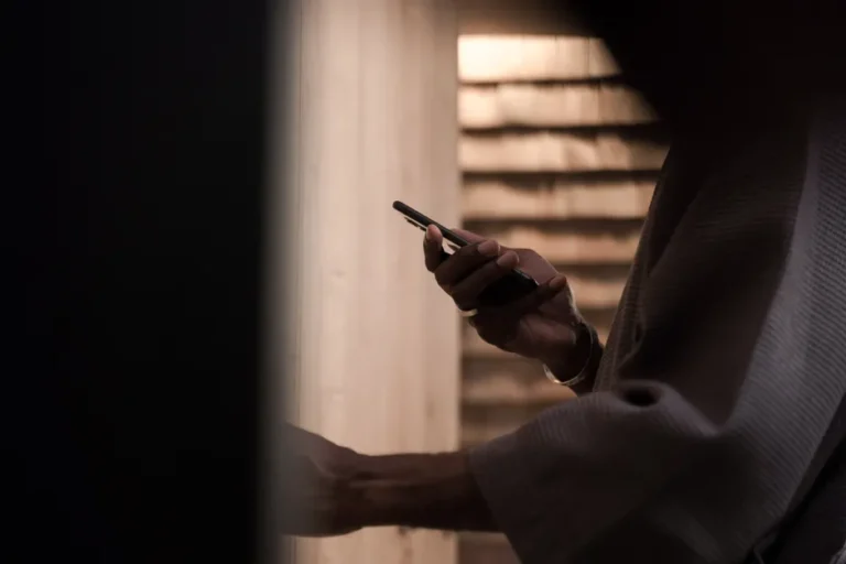 Gemini dans Apple Intelligence en 2026 : deux portes pour vos données A person using a smartphone in a dimly lit indoor setting with moody lighting.