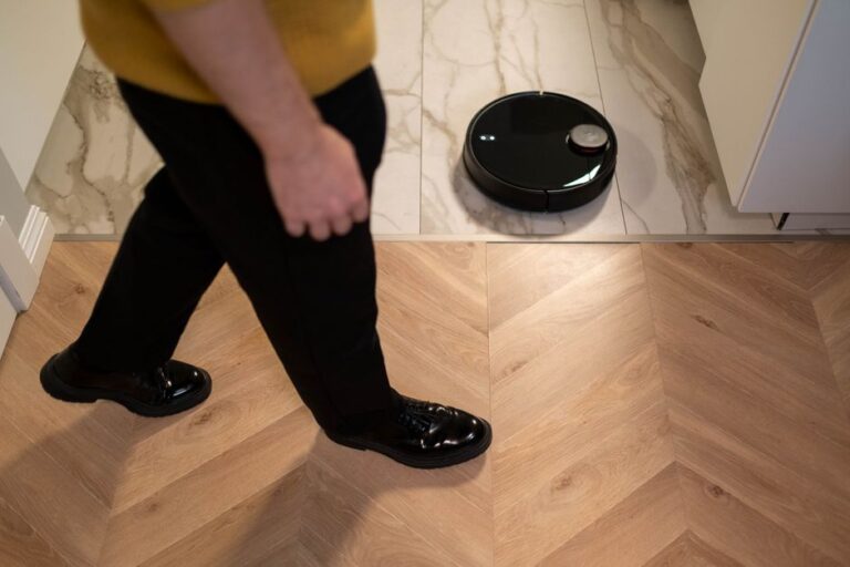 Roborock au CES 2026 : 36 000 Pa et quatre machines A robotic vacuum cleaner operating on a wooden floor, viewed in high angle indoor setting.