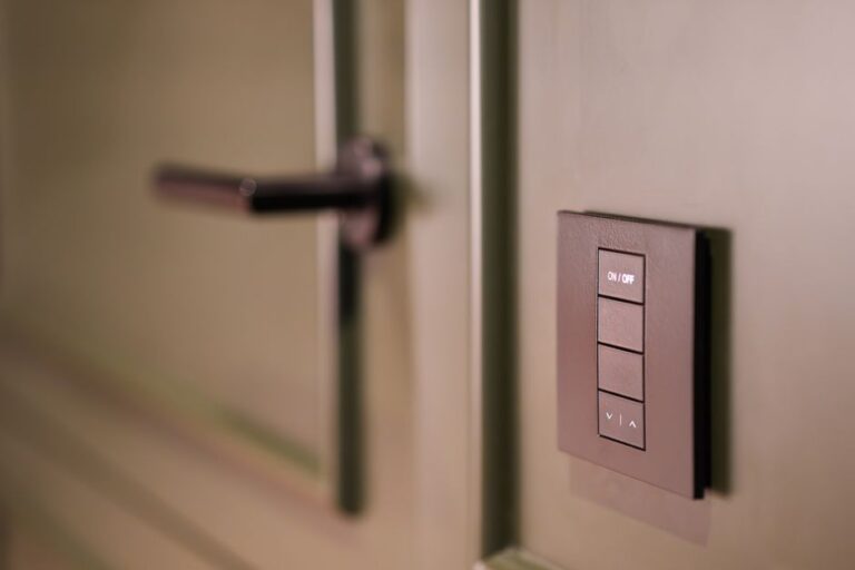 Kwikset Aura Reach à 189 dollars : Matter ouvre, Home Key reste dehors A smart light switch on a wall next to a modern door handle, emphasizing home automation.