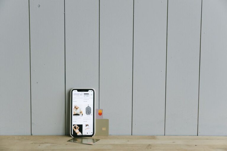 Apple Card : JPMorgan reprend plus de 20 milliards en 2026, mais pas tout de suite A smartphone displaying an ecommerce site with a credit card, set on a wooden surface, depicting online shopping.