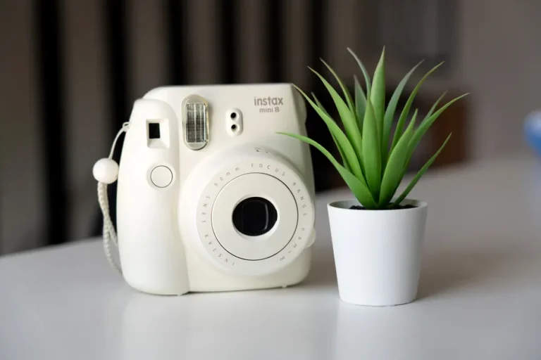 Mac mini M4 à 499,99 dollars le 12 janvier, le M4 Pro négocie A white Instax Mini 8 camera placed next to a potted plant indoors.