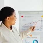 Apple bat un record avec 143,76 milliards au Q1 2026, mais le jardin reste sous pression A woman points at a stock market chart on a whiteboard, explaining financial trends.