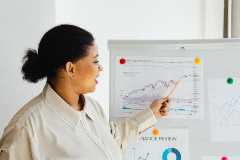 Apple bat un record avec 143,76 milliards au Q1 2026, mais le jardin reste sous pression A woman points at a stock market chart on a whiteboard, explaining financial trends.