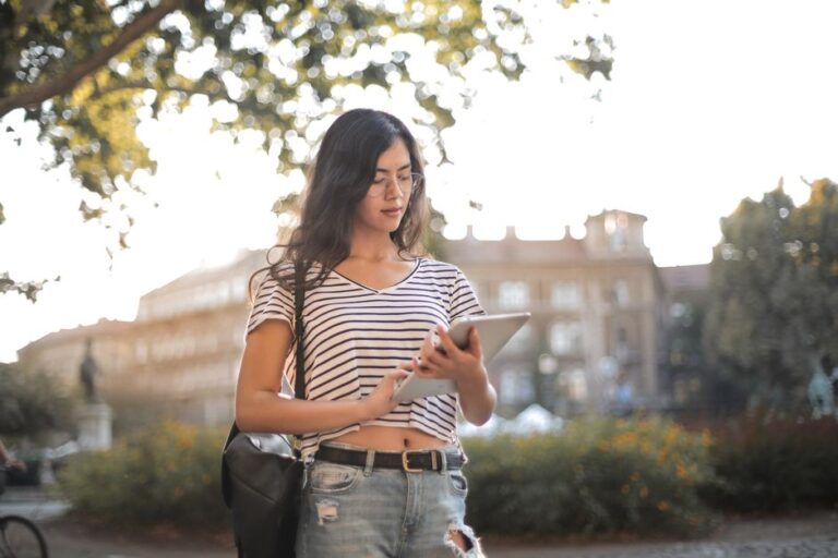 Apple retire la vente séparée du pack Pro Apps à 199,99 $ : Creator Studio prend le relais A young woman in a striped shirt and ripped jeans using a tablet in a sunny park.